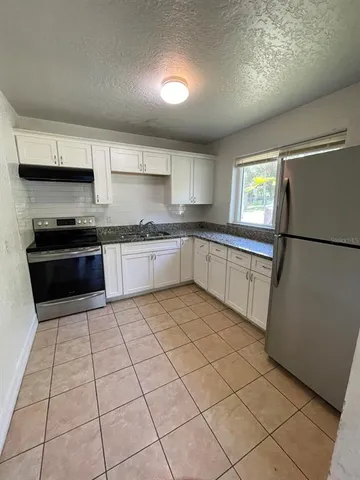 a kitchen with stainless steel appliances granite countertop a refrigerator sink and stove