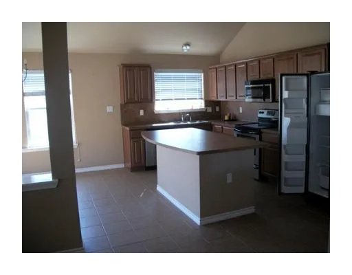 a kitchen with stainless steel appliances granite countertop a refrigerator a sink a stove and island