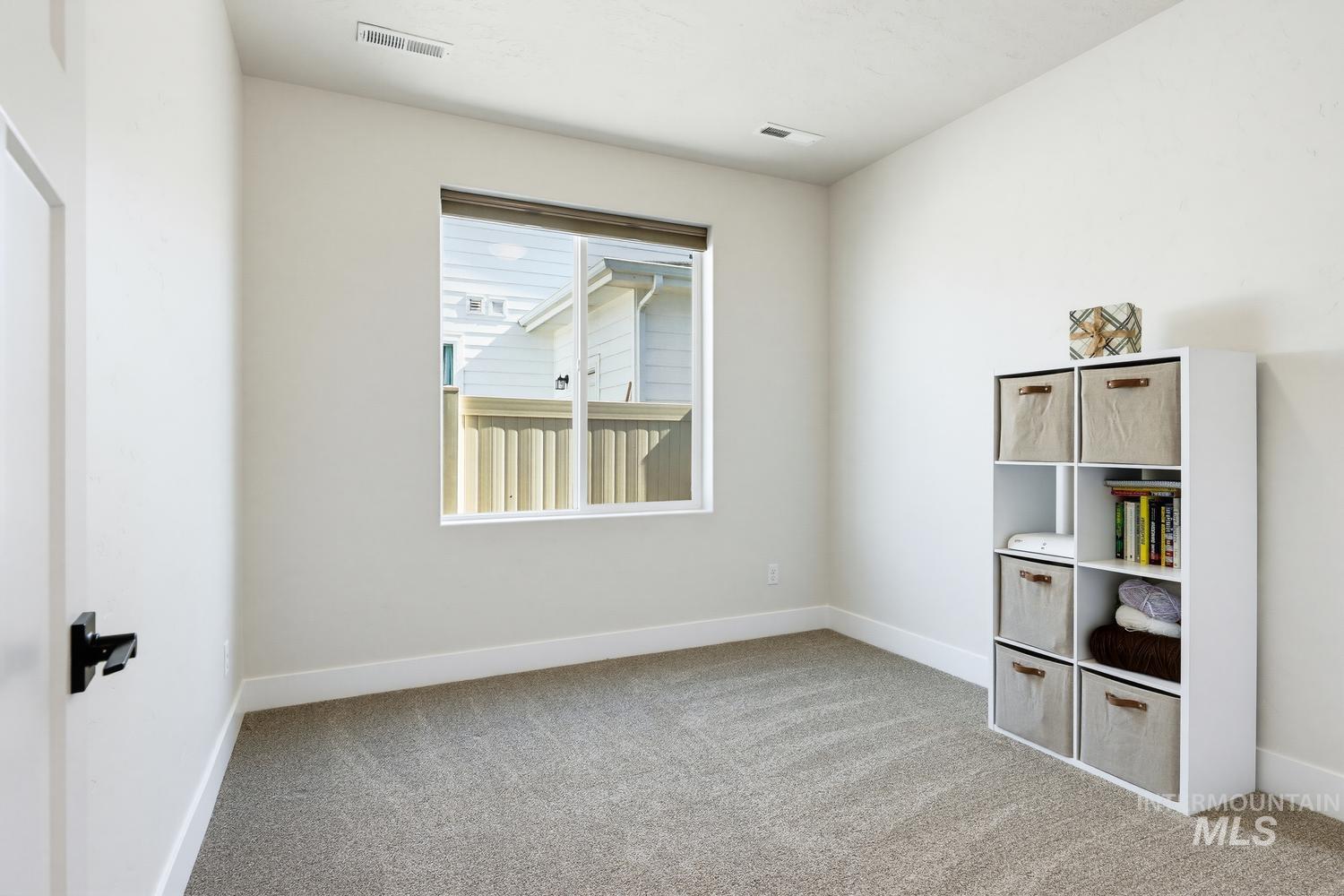 5990 West Ladle Rpds Street Meridian, ID 83646 - Photo 34 of 42 Neutral wall color, window with exterior fencing, light-colored carpeting, white trim, and a white door with black hardware