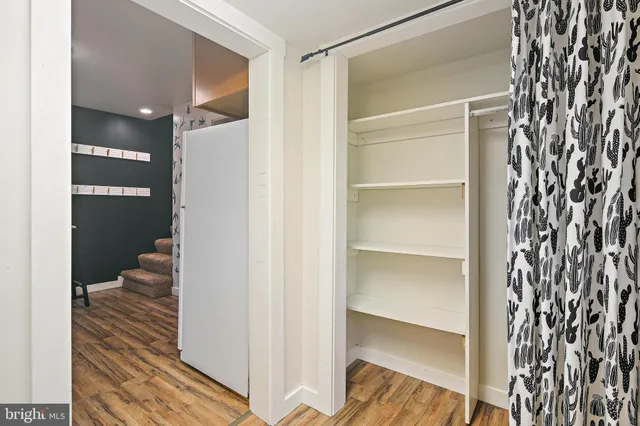 a walk in closet with wooden floor