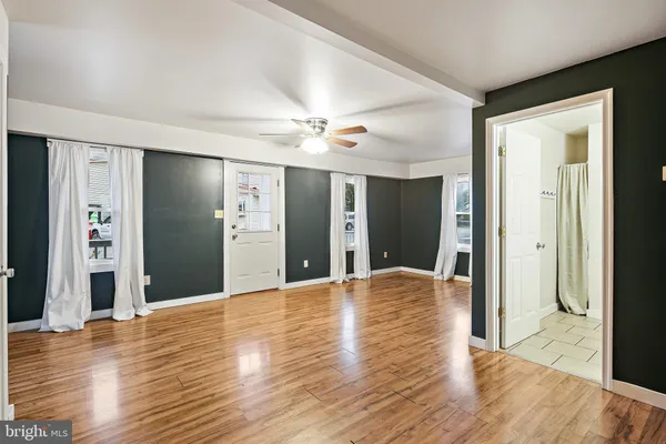 a view of a livingroom with a ceiling fan wooden floor and window