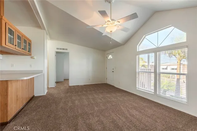 an empty room with chandelier fan and windows