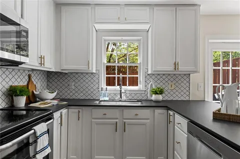 a kitchen with granite countertop a sink a window and cabinets
