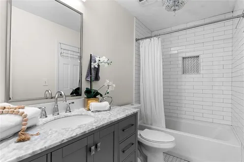a bathroom with a granite countertop sink a toilet and shower