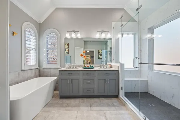 a bathroom with a tub a double vanity sink and a large mirror