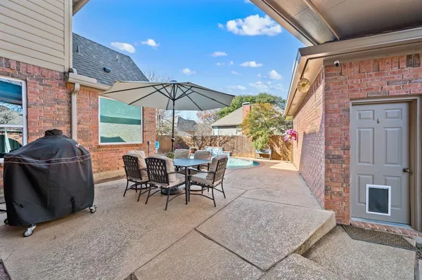 a view of a patio with a table and chairs under an umbrella