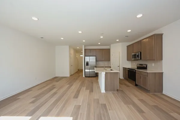 a kitchen with stainless steel appliances kitchen island granite countertop a stove a refrigerator a sink a microwave oven with white cabinets and wooden floor