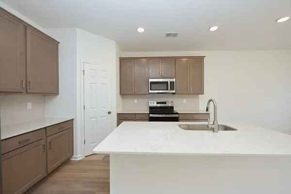 a kitchen with stainless steel appliances kitchen island a sink dishwasher a refrigerator and a stove with wooden floor