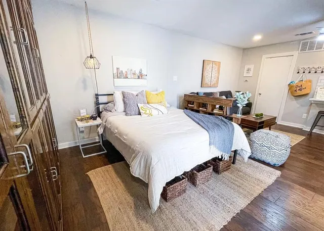 a spacious bedroom with a bed and wooden floor