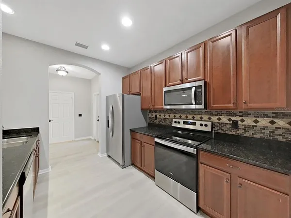 a kitchen with granite countertop wooden cabinets and stainless steel appliances
