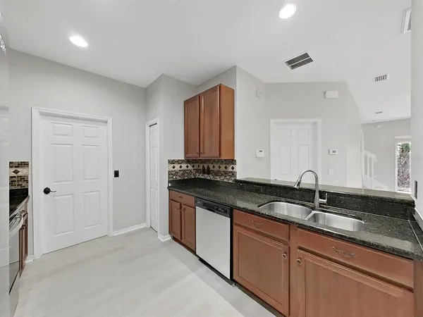 a kitchen with stainless steel appliances granite countertop a refrigerator a stove and a sink