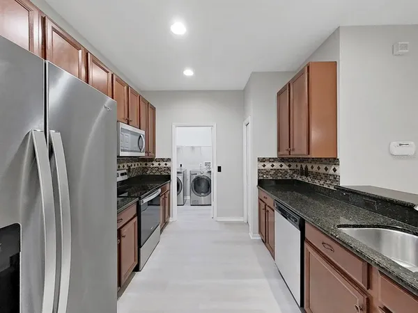 a kitchen with stainless steel appliances granite countertop a refrigerator stove and a sink