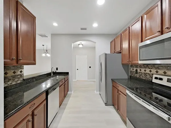 a kitchen with stainless steel appliances granite countertop a stove a sink and a refrigerator