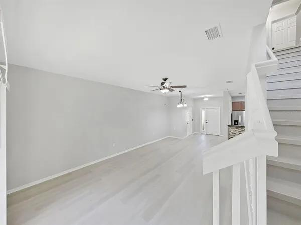 a view of a room with wooden floor and ceiling fan
