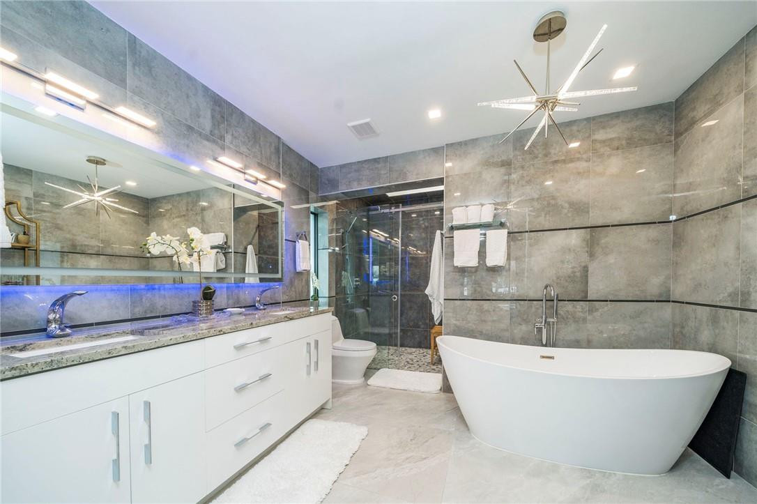 730 Northeast 69th Street Boca Raton, FL 33487 - Photo 16 of 32 a bathroom with a bathtub a double vanity sink and a mirror