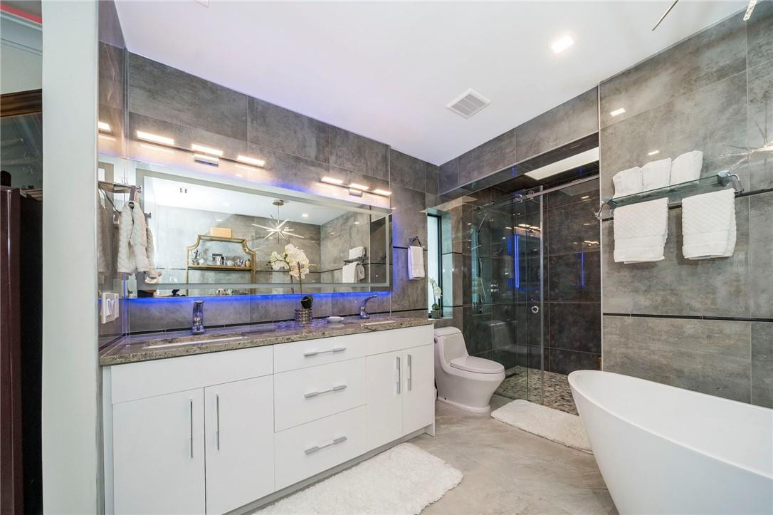 730 Northeast 69th Street Boca Raton, FL 33487 - Photo 17 of 32 a bathroom with a double vanity sink toilet mirror and bathtub