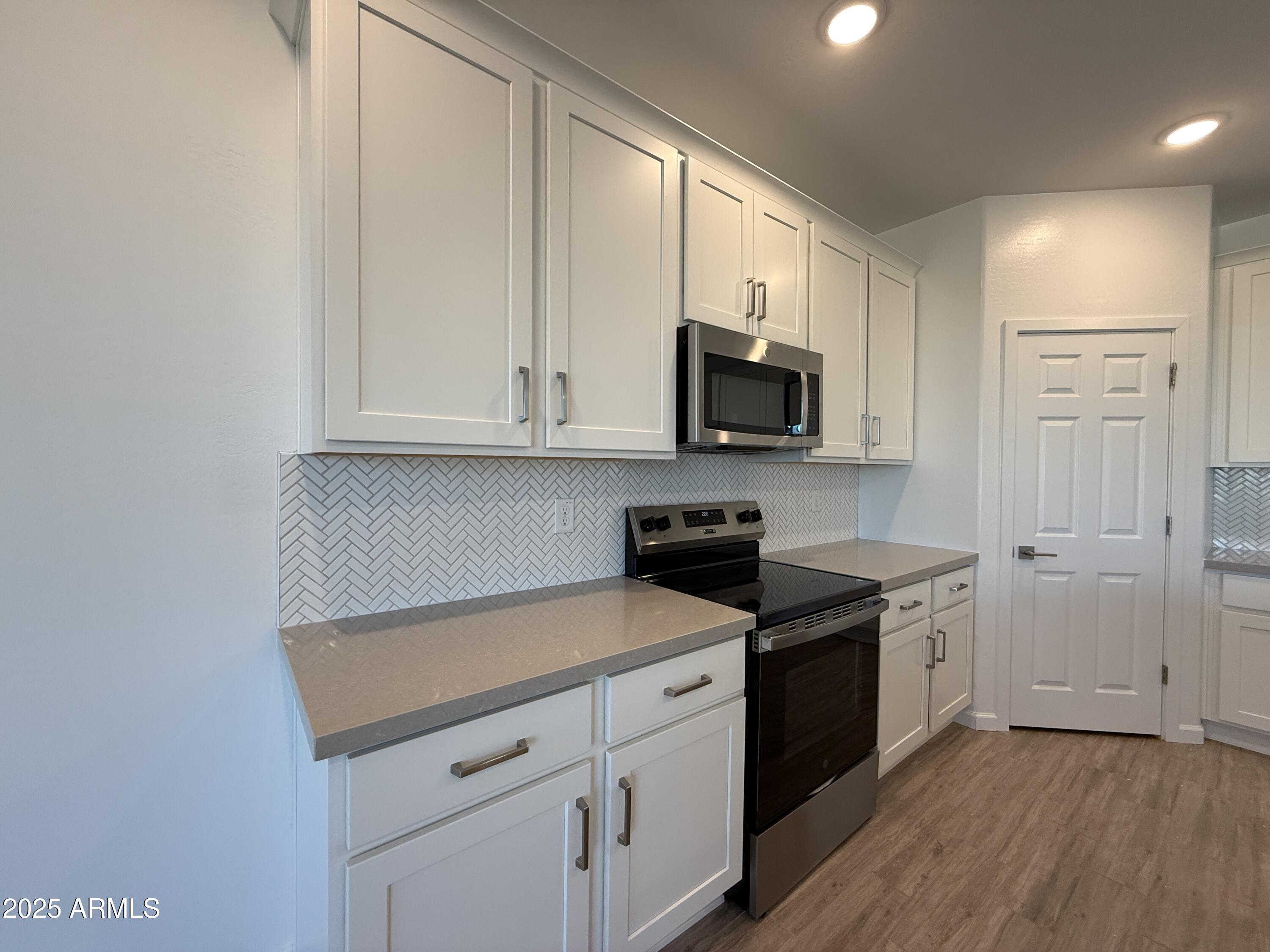 9628 West Tamarisk Avenue Tolleson, AZ 85353 - Photo 15 of 37 a kitchen with stainless steel appliances granite countertop a stove a sink and a microwave