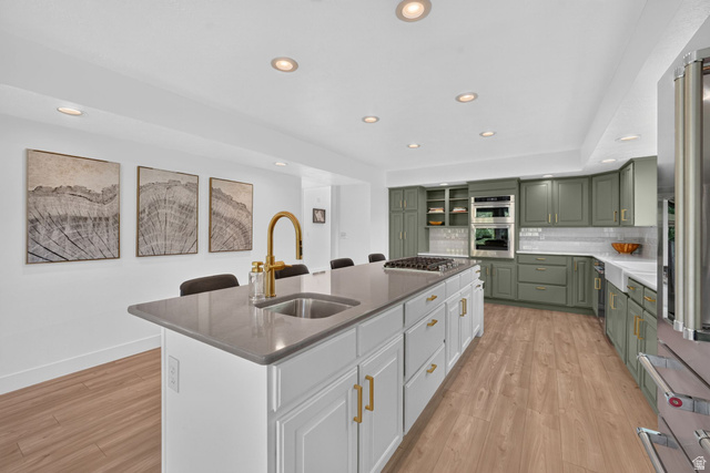 1979 Cave Hollow Way Bountiful, UT 84010 - Photo 15 of 59 Spacious kitchen featuring a large central island with a gold-tone faucet and integrated sink, light wood-finish flooring, recessed lighting, and sage green cabinetry with gold-tone hardware