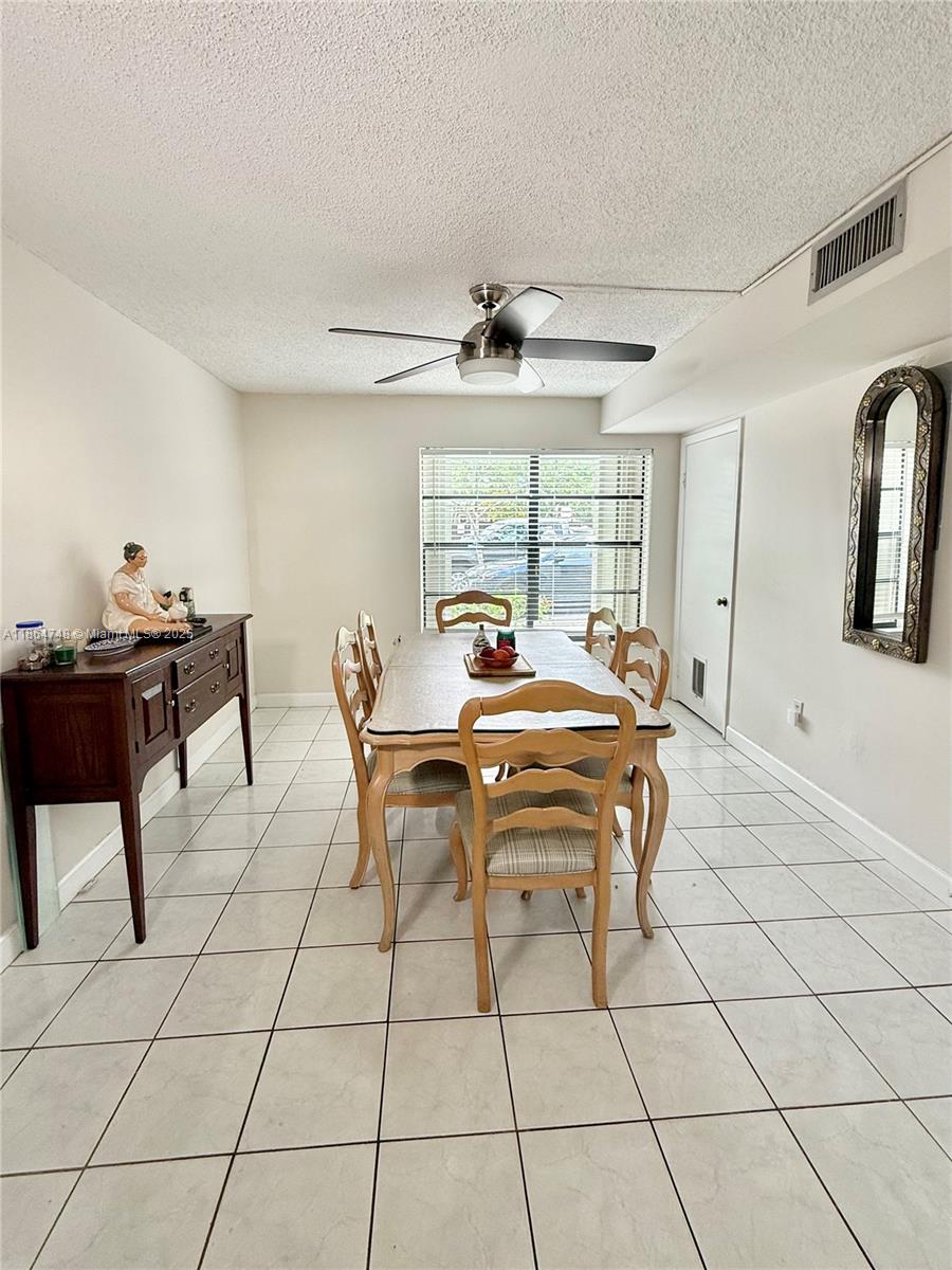 11028 Southwest 132nd Place, Unit 244 Miami, FL 33186 - Photo 11 of 25 a view of a dining room with furniture and a chandelier fan