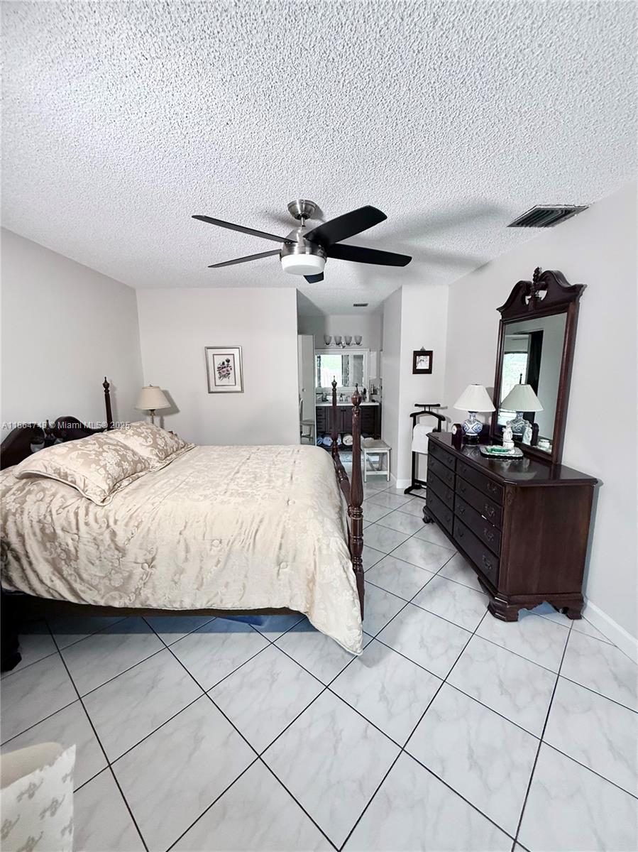 11028 Southwest 132nd Place, Unit 244 Miami, FL 33186 - Photo 17 of 25 a bedroom with a bed and a ceiling fan