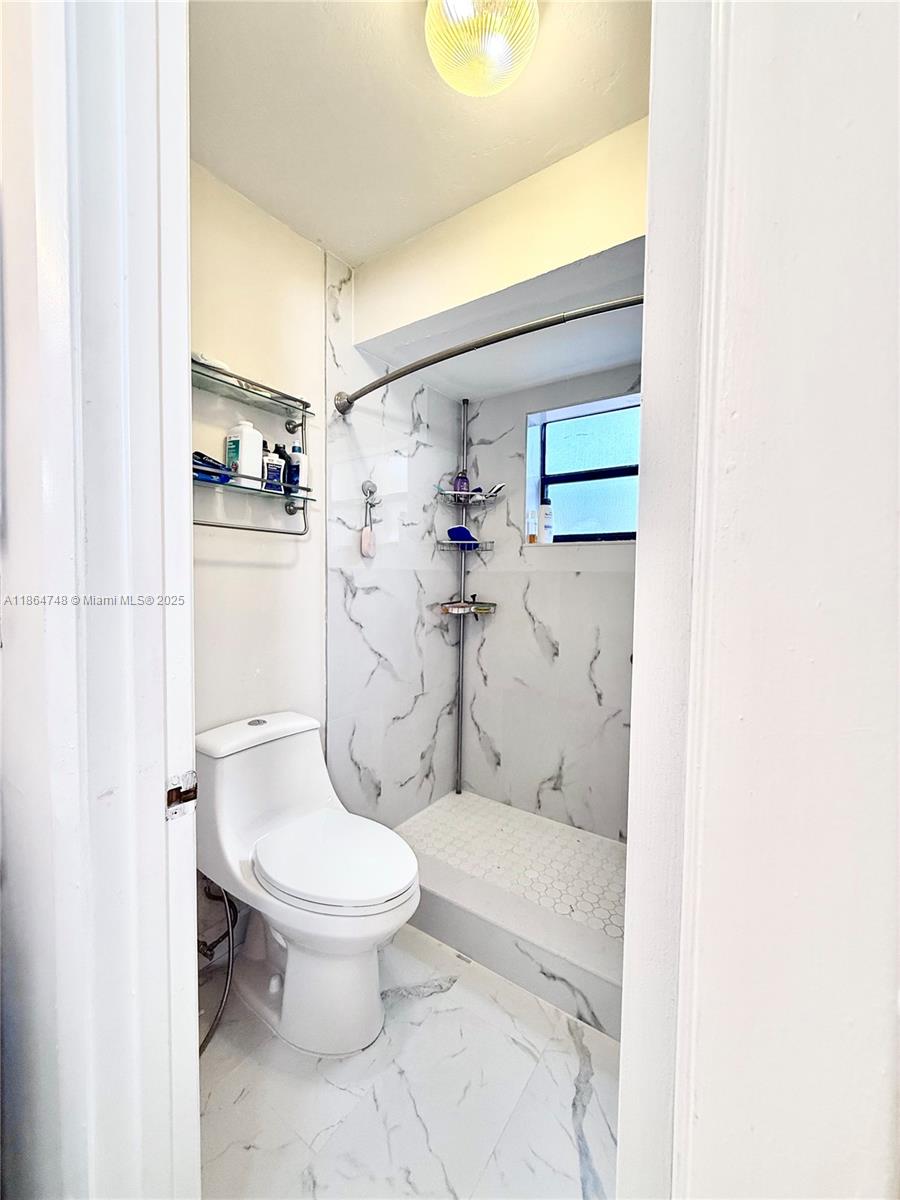 11028 Southwest 132nd Place, Unit 244 Miami, FL 33186 - Photo 20 of 25 a bathroom with a granite countertop toilet and a shower