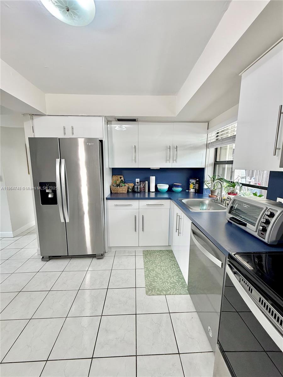 11028 Southwest 132nd Place, Unit 244 Miami, FL 33186 - Photo 7 of 25 a large kitchen with stainless steel appliances granite countertop a refrigerator and a stove top oven