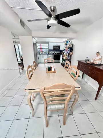 a dining room with furniture and a chandelier fan