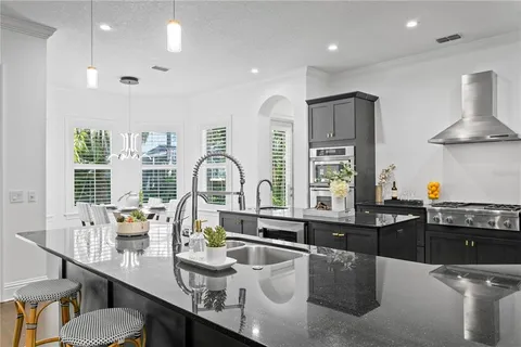 a kitchen with stainless steel appliances granite countertop a stove a sink dishwasher a dining table and chairs with wooden floor