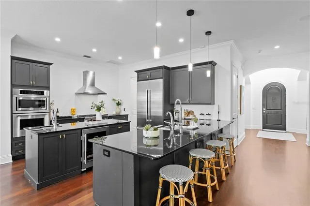 a kitchen with stainless steel appliances granite countertop a stove top oven a sink dishwasher a dining table and chairs with wooden floor