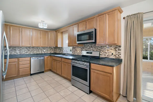 a kitchen with stainless steel appliances granite countertop a stove a sink and a microwave