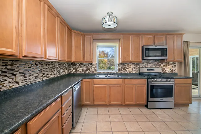 a kitchen with stainless steel appliances granite countertop a sink a stove a microwave cabinets and a counter top space