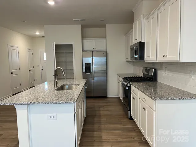 a kitchen with stainless steel appliances granite countertop a sink stove and refrigerator