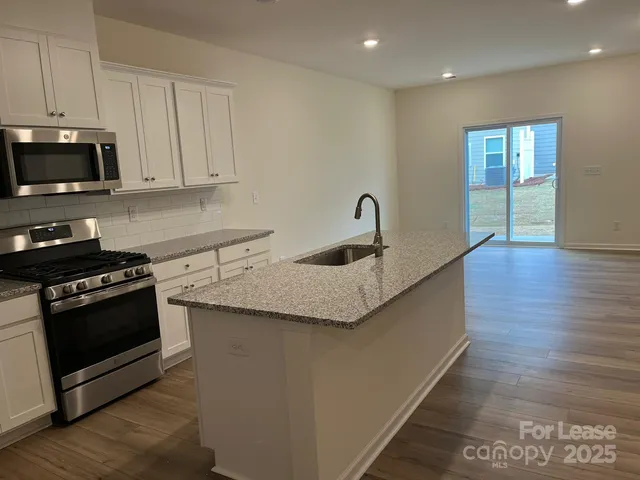 a kitchen with granite countertop a sink and a stove top oven