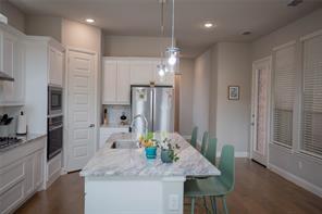 473 Chambers Place Fairview, TX 75069 - Photo 11 of 20 a kitchen with stainless steel appliances kitchen island granite countertop a refrigerator a stove a sink and white cabinets with wooden floor