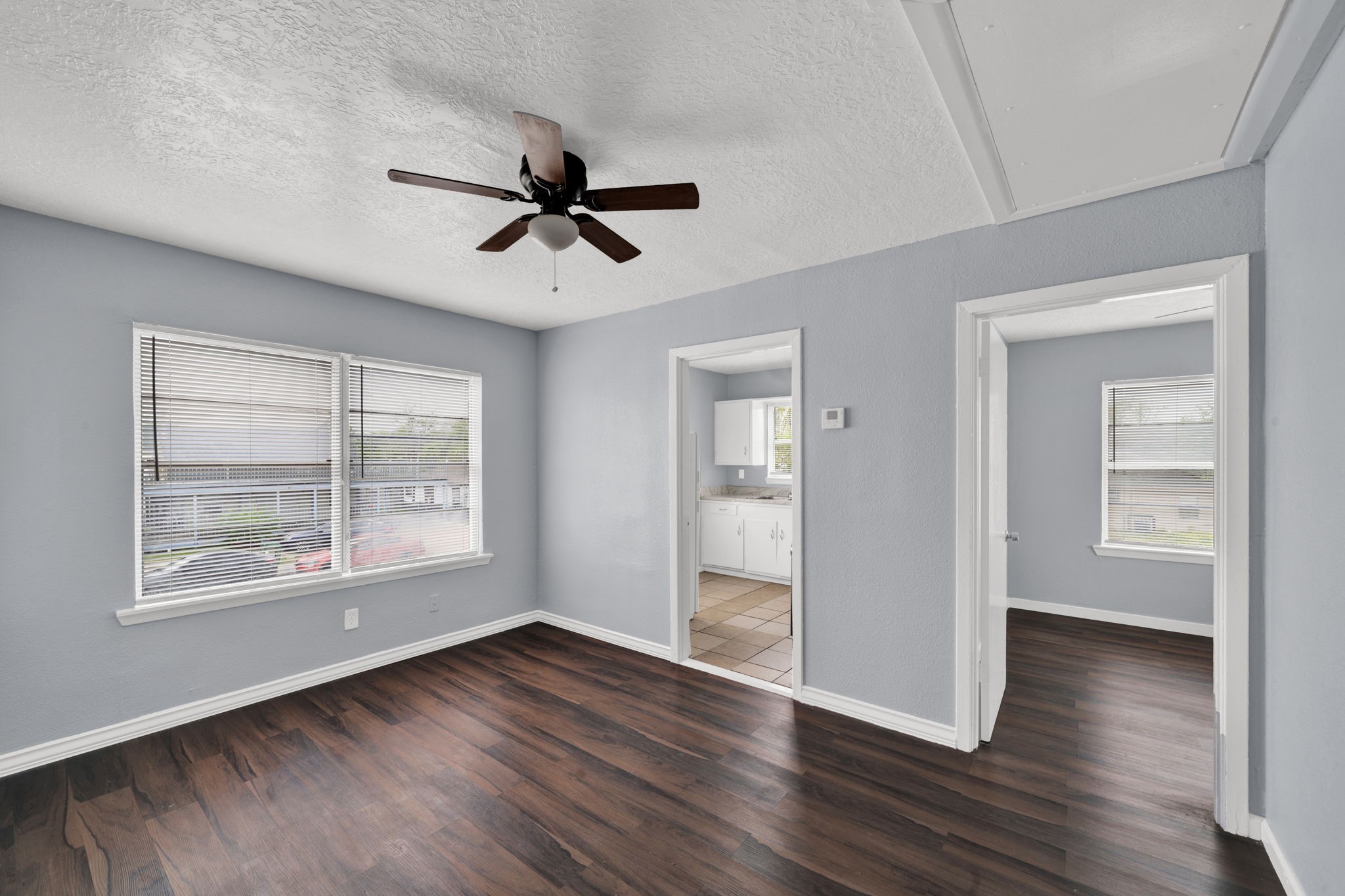 a view of empty room with wooden floor and fan