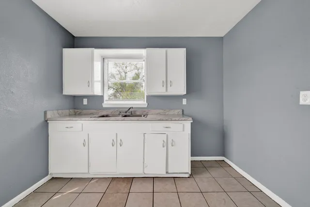 a kitchen with granite countertop white cabinets white appliances a sink and a window