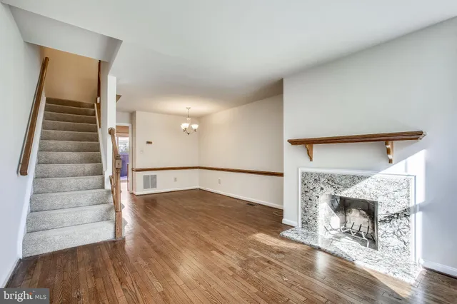 a view of an empty room with wooden floor and a fireplace