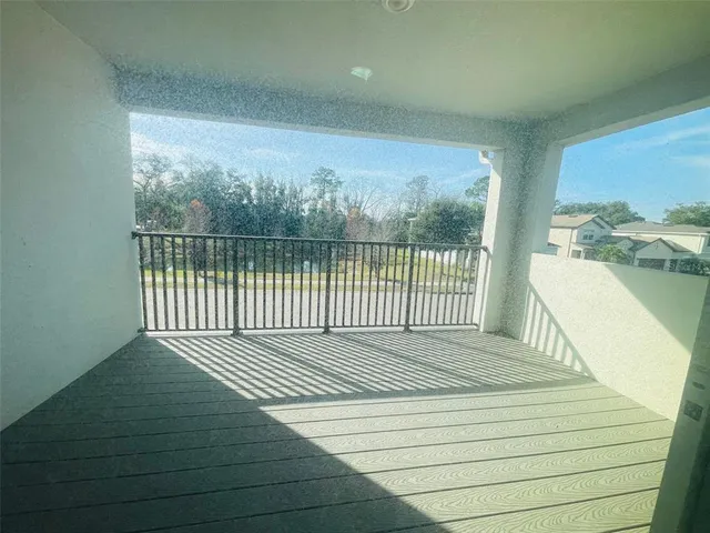 a balcony with wooden floor next to a yard