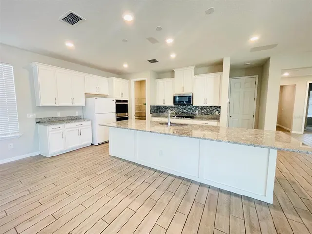 a large kitchen with cabinets and wooden floor