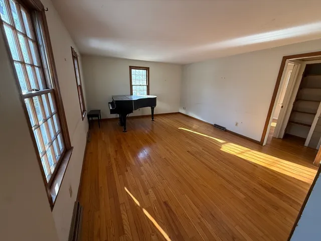 a view of an empty room with wooden floor and stairs