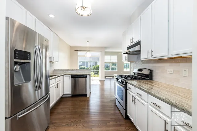 a kitchen with stainless steel appliances granite countertop a refrigerator a stove and a sink