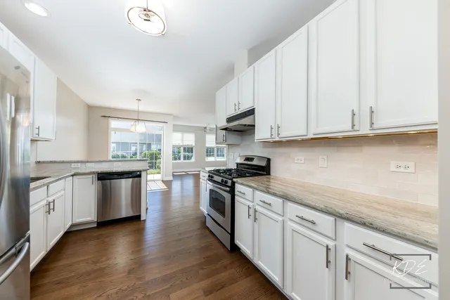 a kitchen with stainless steel appliances granite countertop a stove a sink and white cabinets