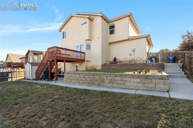 712 Rye Ridge Road Fountain, CO 80817 - Photo 40 of 45 Back of house with stairs, a patio area, stucco siding, a fenced backyard, and a storage unit