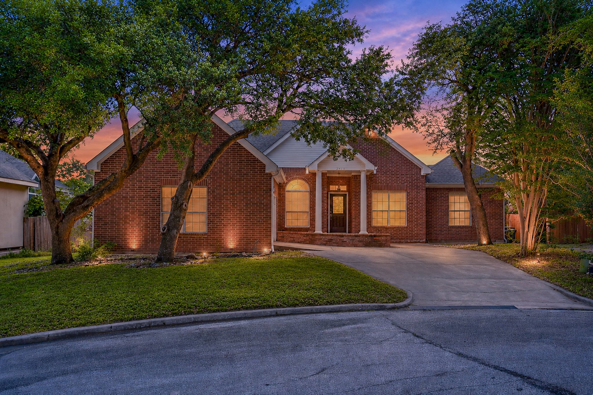 11737 Rydalwater Lane Austin, TX 78754 - Photo 1 of 40 Brick exterior residence featuring a covered entry, arched windows, a concrete driveway, and mature landscaping