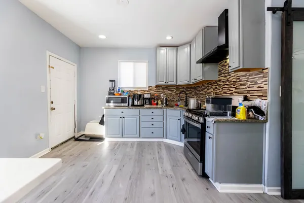 a kitchen with stainless steel appliances a stove top oven a sink dishwasher and a refrigerator with wooden floor