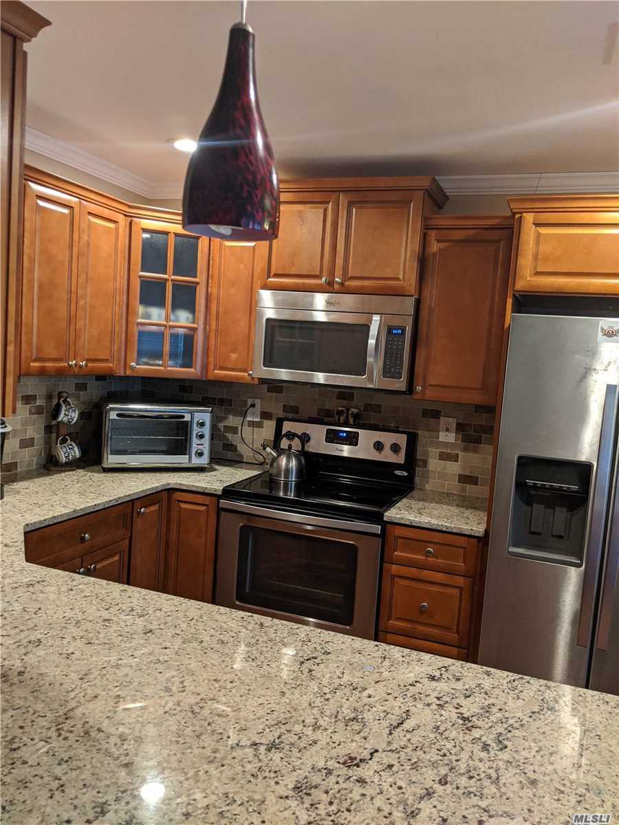 409 Weymouth Court, Unit E Ridge, NY 11961 - Photo 1 of 1 a kitchen with stainless steel appliances granite countertop a stove a sink and a microwave