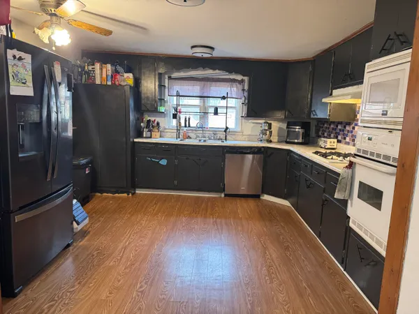 a kitchen with stainless steel appliances wooden floor sink and wooden cabinets