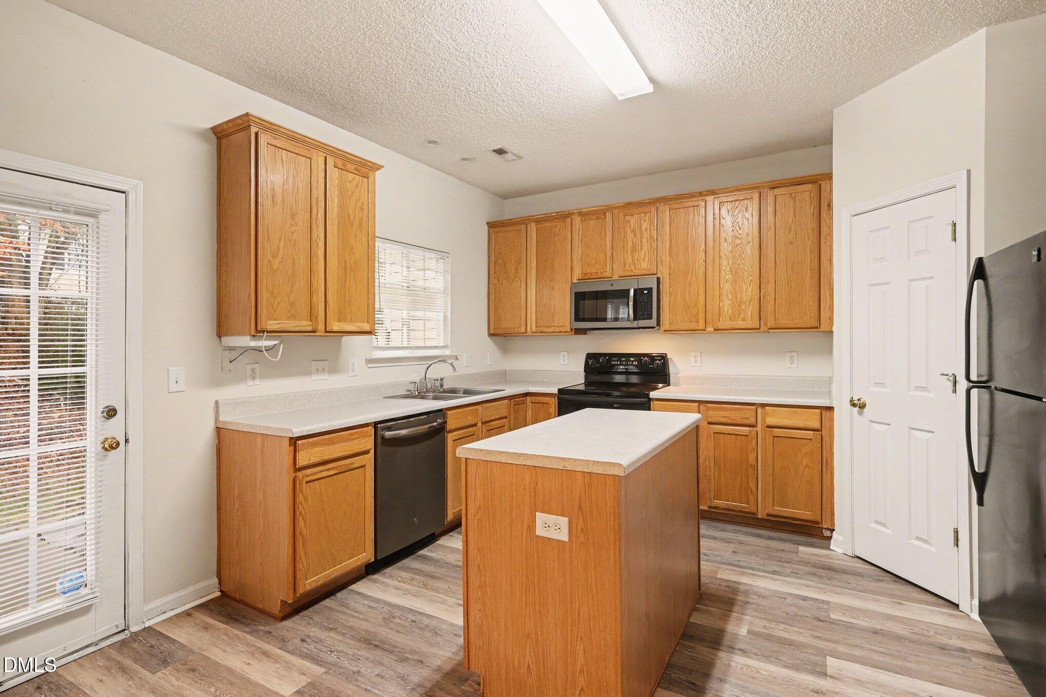 10947 Pendragon Place Raleigh, NC 27614 - Photo 11 of 21 a kitchen with stainless steel appliances granite countertop a refrigerator a sink dishwasher a stove top oven a sink and dishwasher with wooden floor
