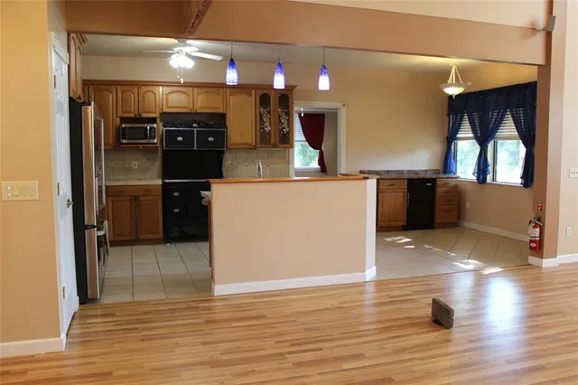 a kitchen with stainless steel appliances wooden floor and living room