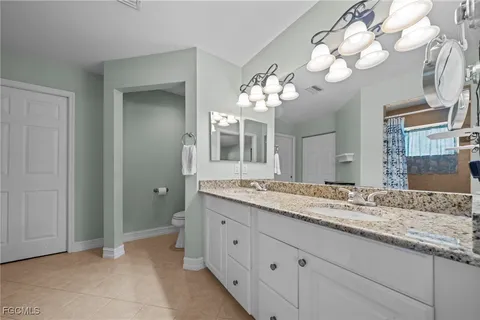 a bathroom with a granite countertop double vanity sink and a mirror